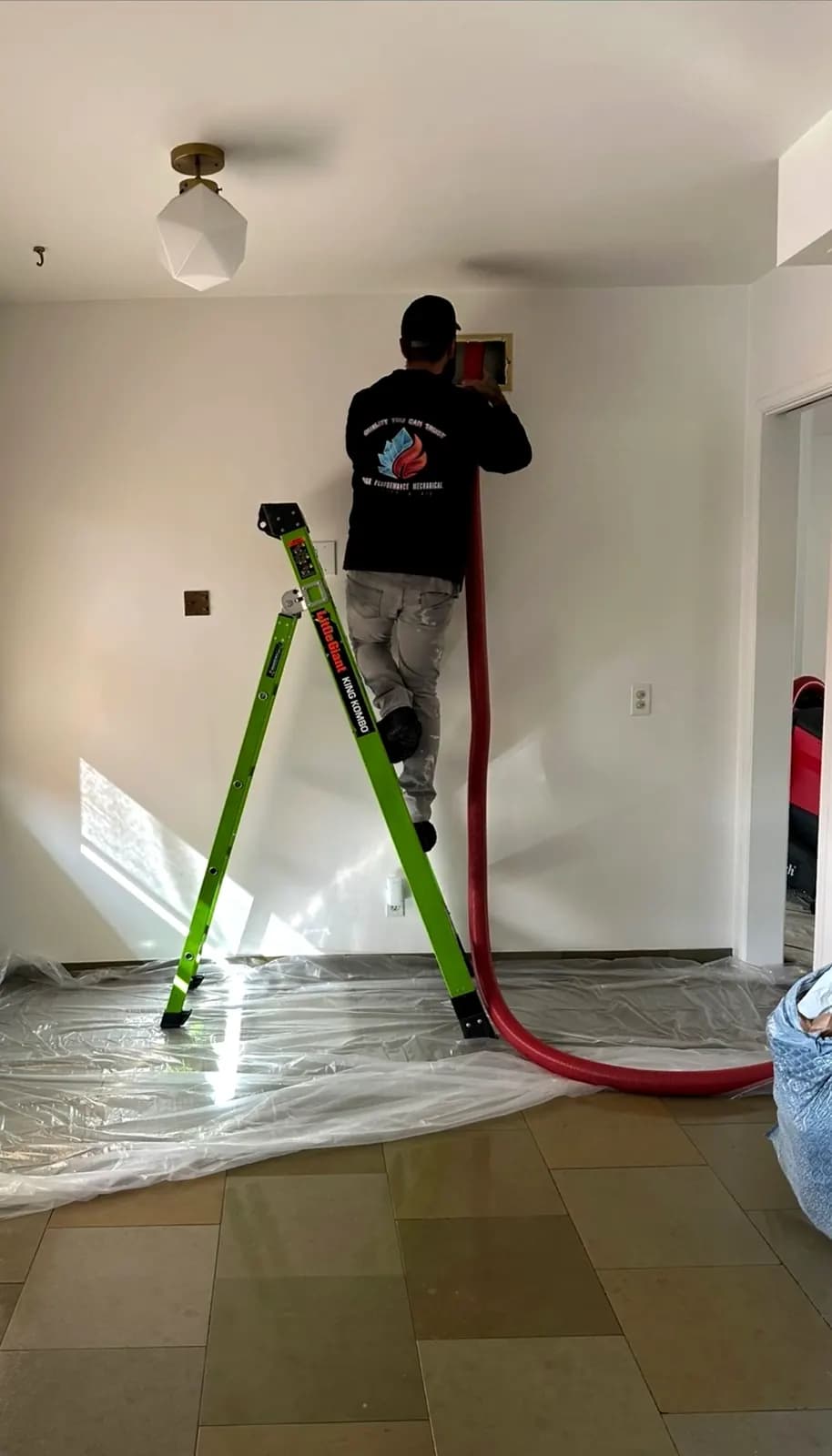 Technician cleaning air ducts in a home with floors protected