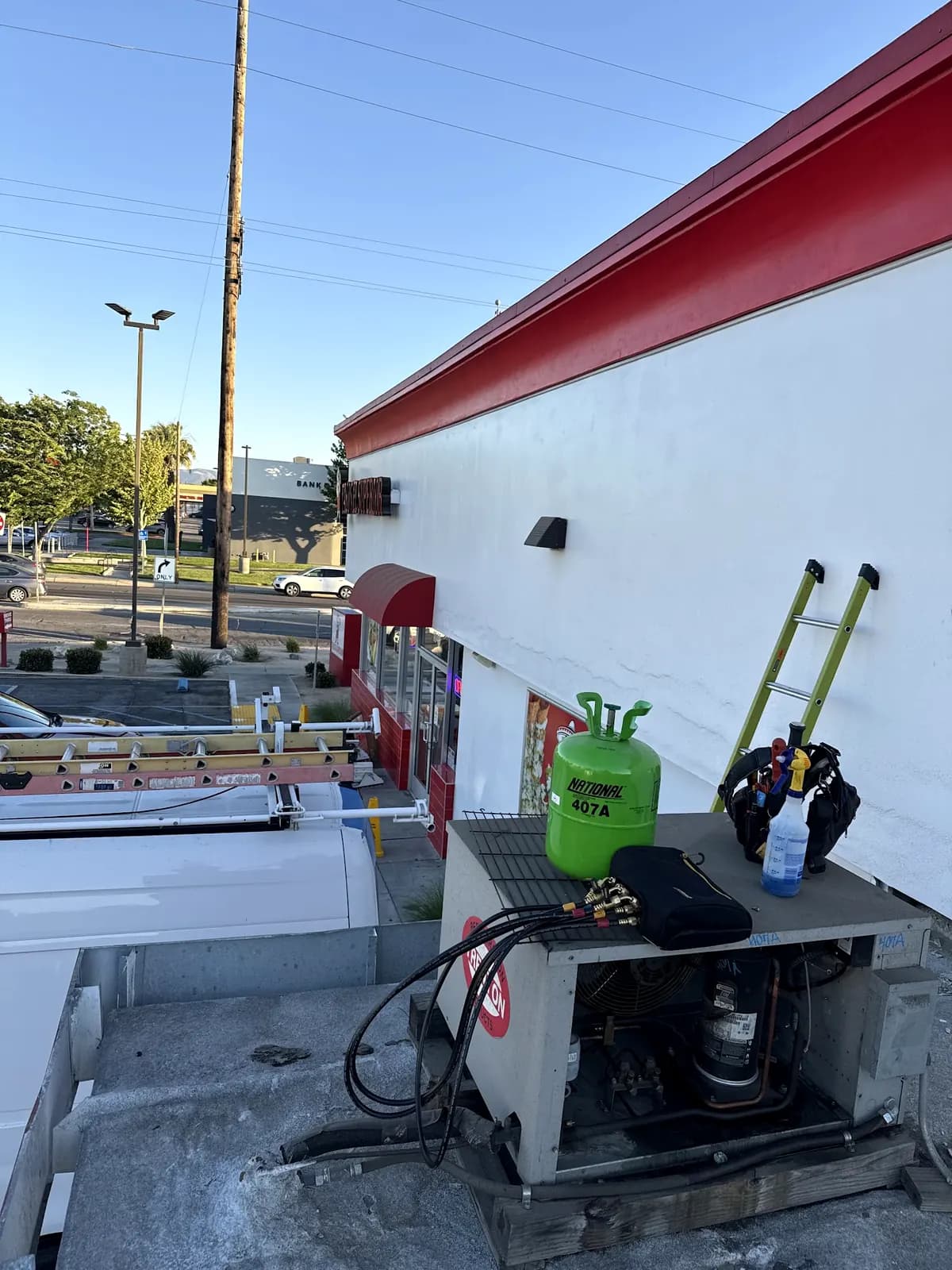 Refrigerant tank and tools beside a rooftop unit