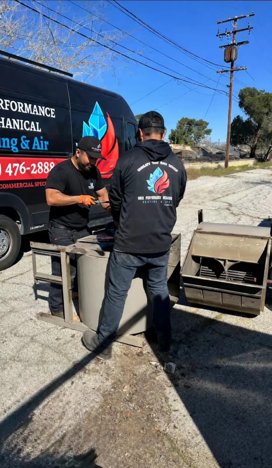 Two technicians preparing ductwork beside the company van