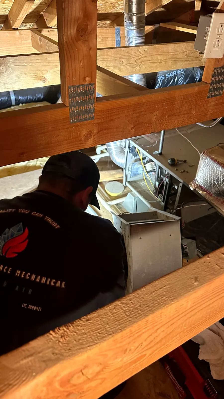 Technician servicing a furnace in an attic