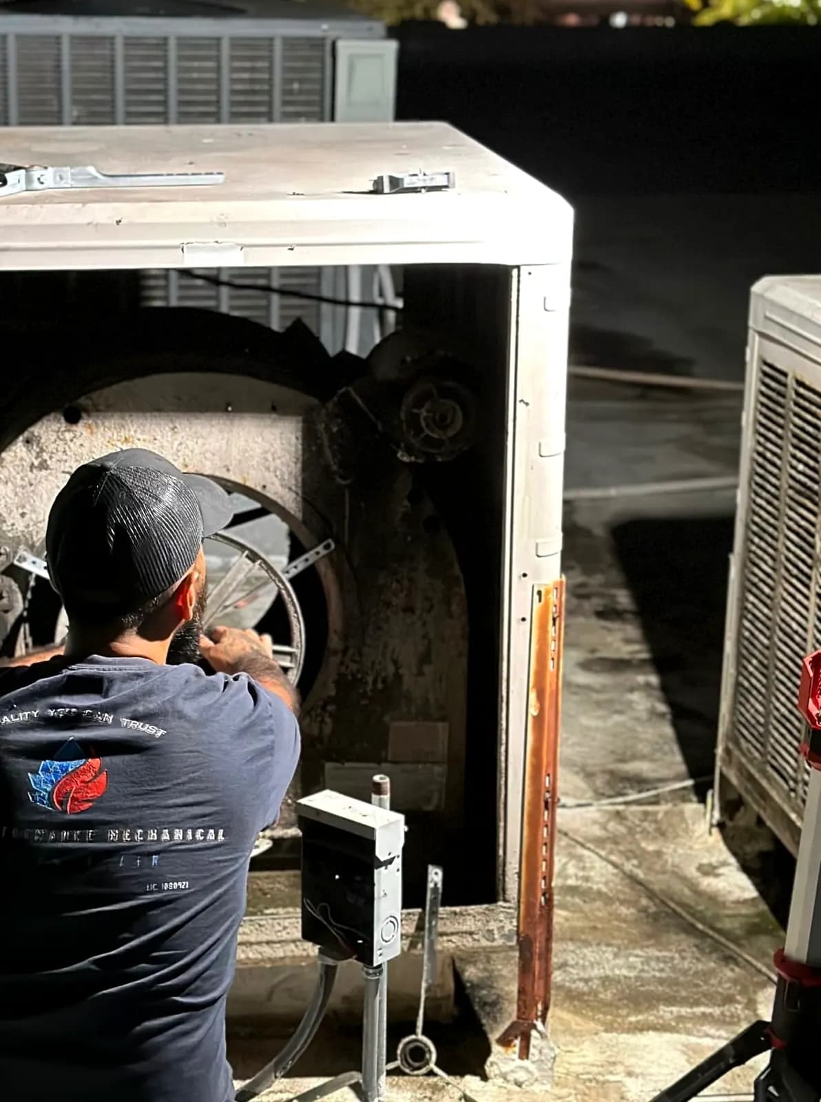 Technician servicing a blower inside an HVAC cabinet
