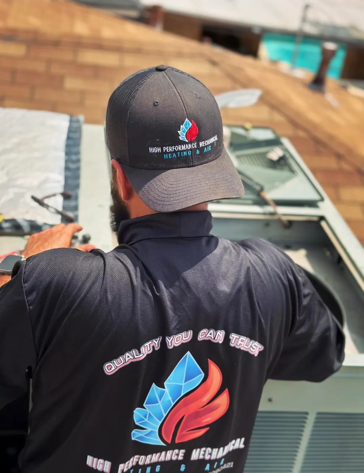 Technician in a High Performance Mechanical cap and shirt working on a rooftop unit