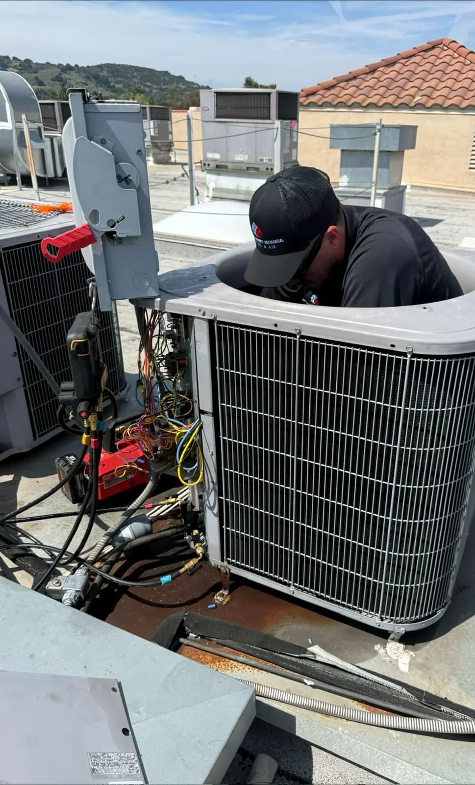 Technician working inside an outdoor condenser on a rooftop