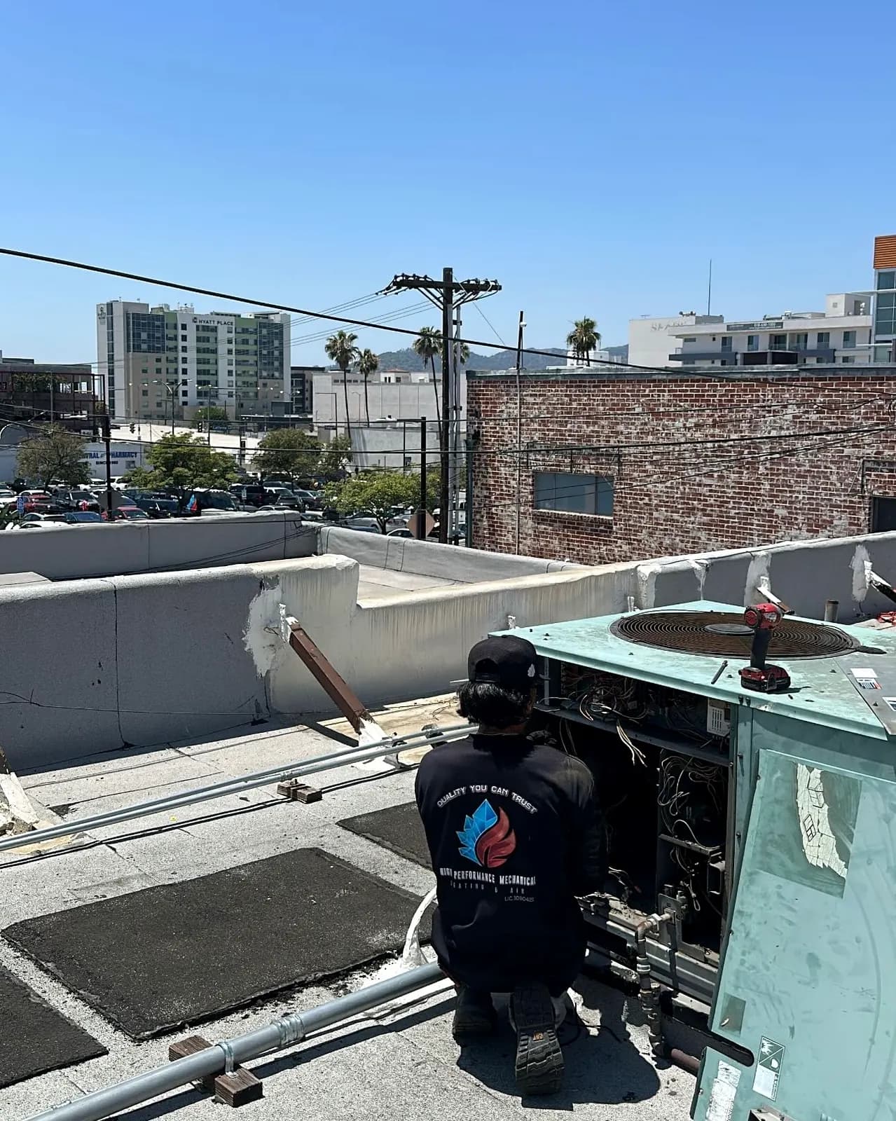 Technician servicing a commercial rooftop unit with the city skyline behind