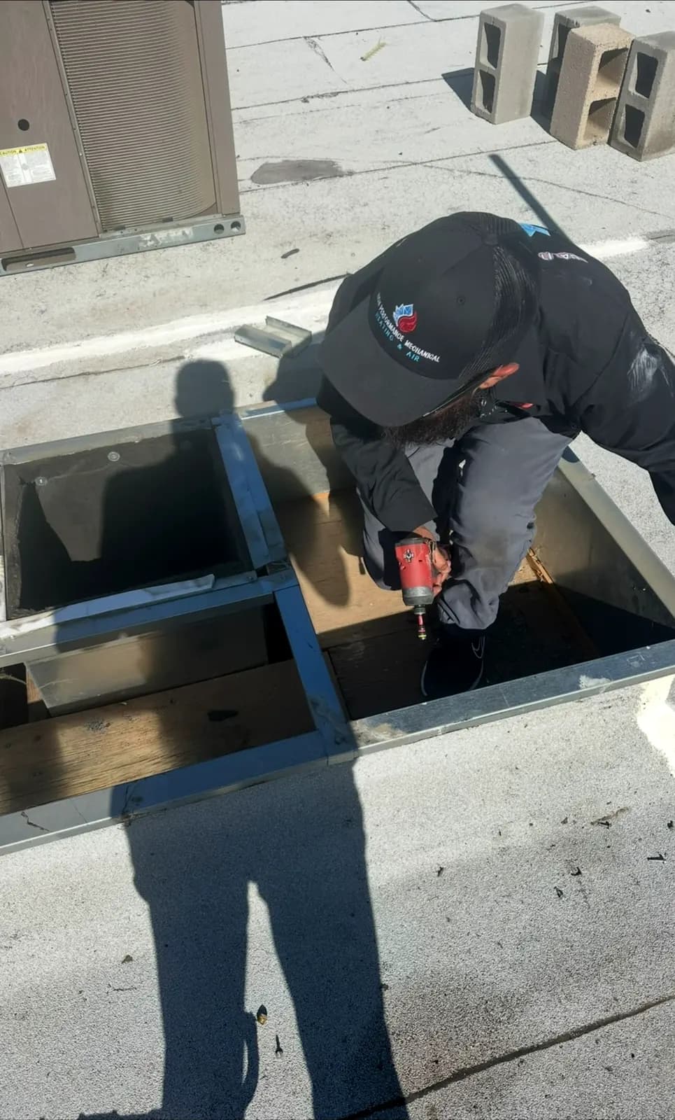 Technician working on a rooftop unit curb and duct opening