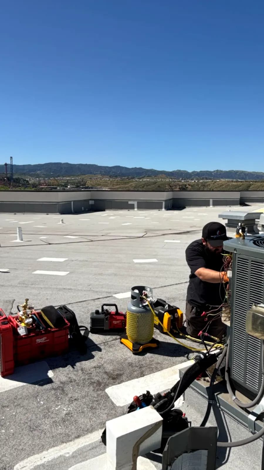 Technician checking refrigerant with gauges on a rooftop