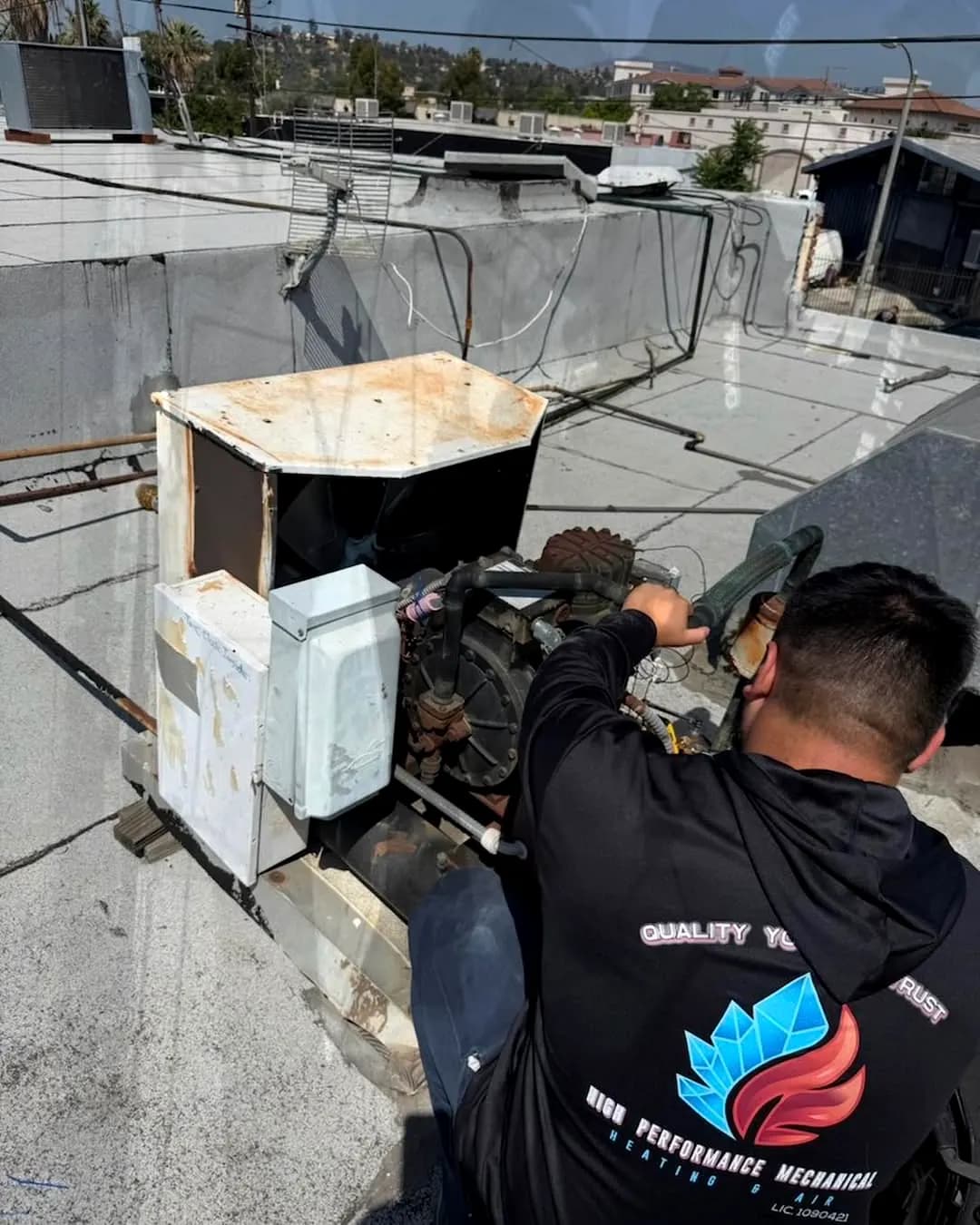 Technician repairing an AC condenser on a rooftop